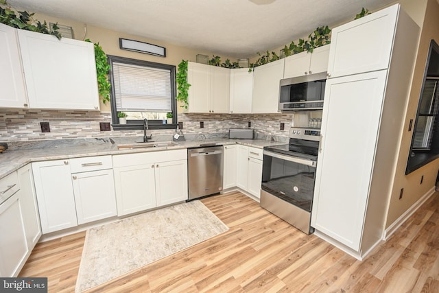 kitchen featuring appliances with stainless steel finishes, light wood-type flooring, white cabinetry, and sink