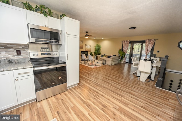 kitchen with decorative backsplash, stainless steel appliances, ceiling fan, light hardwood / wood-style floors, and white cabinetry