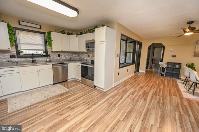 kitchen featuring decorative backsplash, appliances with stainless steel finishes, sink, white cabinets, and light hardwood / wood-style floors