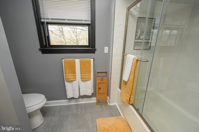 bathroom with toilet and shower / bath combination with glass door