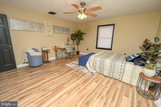 bedroom featuring ceiling fan, light hardwood / wood-style flooring, and a textured ceiling