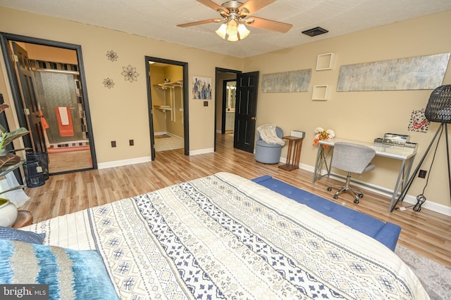 bedroom with a closet, connected bathroom, a spacious closet, and hardwood / wood-style floors