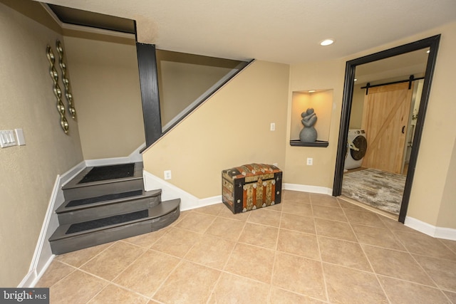 interior space with a barn door, washer / clothes dryer, and light tile patterned floors