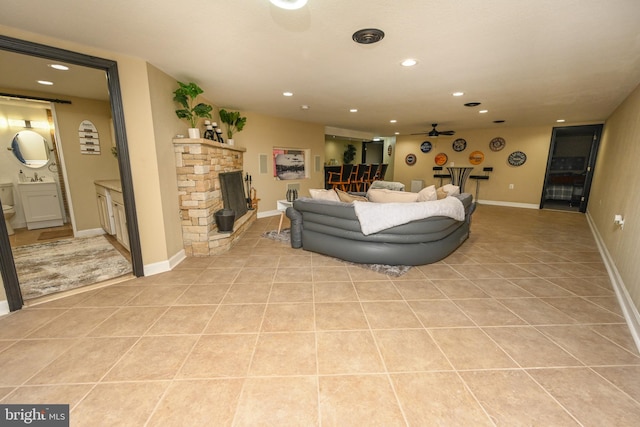 living room with a stone fireplace and light tile patterned floors