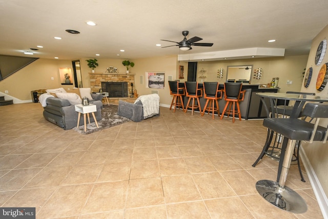 living room featuring bar area, ceiling fan, a fireplace, and light tile patterned flooring