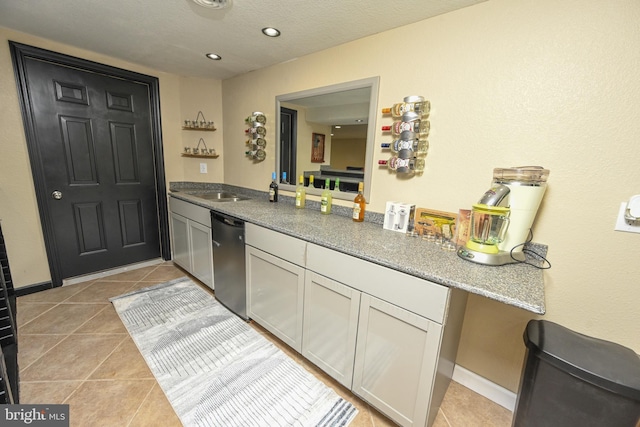 kitchen with dishwasher, stone counters, kitchen peninsula, light tile patterned floors, and white cabinetry