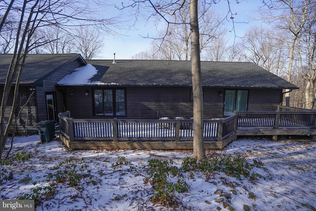 snow covered back of property with a wooden deck