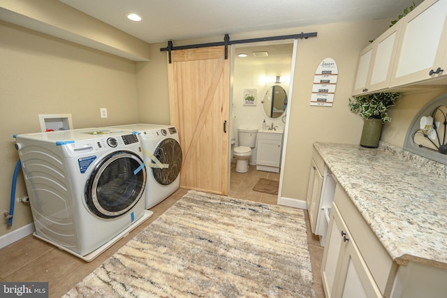 washroom featuring cabinets, a barn door, and washing machine and dryer