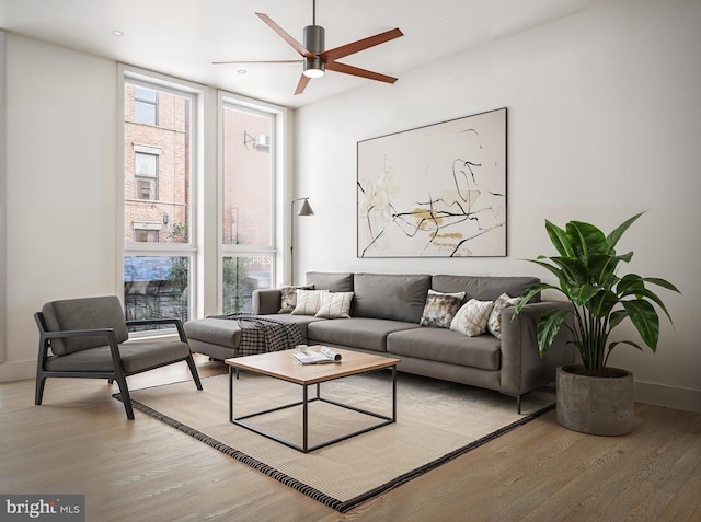 living room featuring ceiling fan, expansive windows, and light wood-type flooring