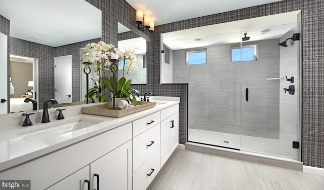 bathroom with tile patterned floors, vanity, a shower with door, and tile walls