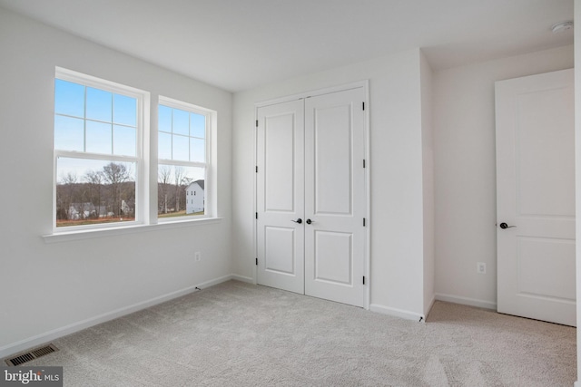 unfurnished bedroom with light colored carpet and a closet