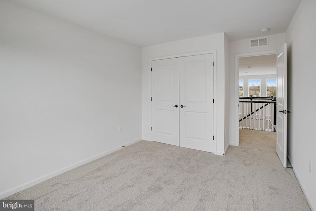 unfurnished bedroom featuring a closet and light colored carpet