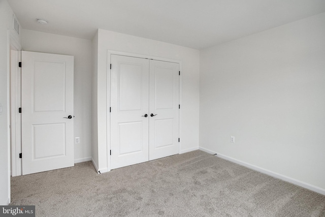 unfurnished bedroom featuring light carpet and a closet