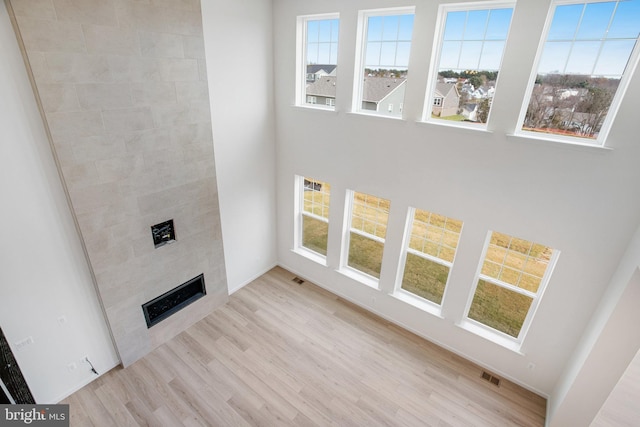 unfurnished living room with a tile fireplace and light wood-type flooring