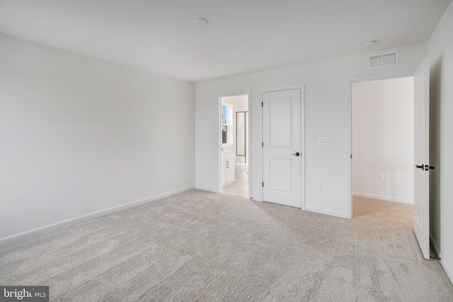 unfurnished bedroom with ensuite bathroom and light colored carpet