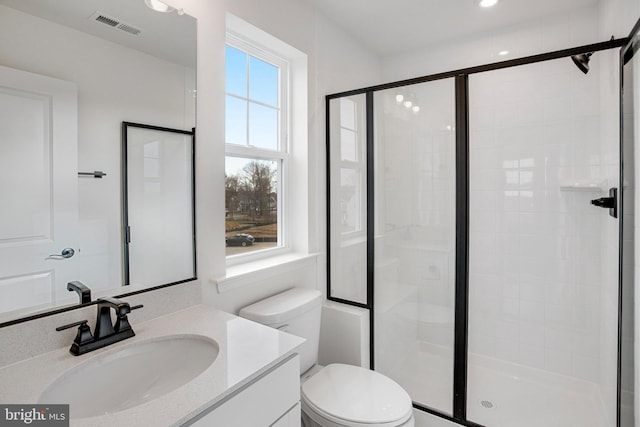 bathroom with vanity, toilet, and a shower with door