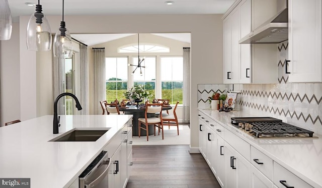 kitchen with white cabinets, wall chimney exhaust hood, sink, pendant lighting, and a chandelier