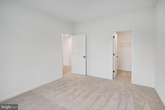 unfurnished bedroom featuring light colored carpet, a spacious closet, and a closet