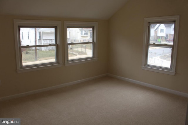 carpeted spare room featuring vaulted ceiling