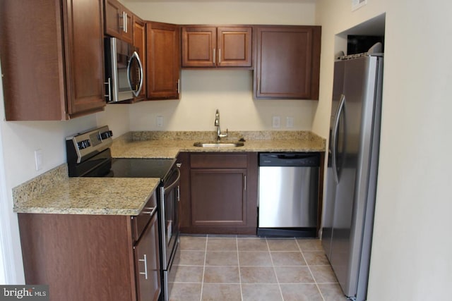 kitchen with light stone countertops, sink, light tile patterned floors, and stainless steel appliances