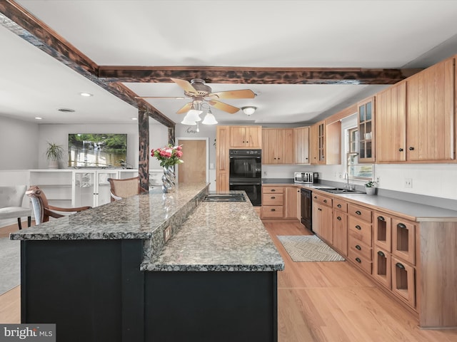 kitchen featuring black appliances, stone counters, plenty of natural light, and sink