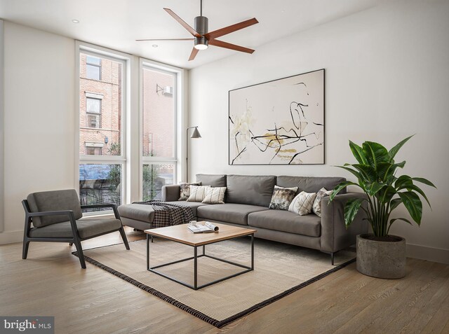 living room featuring light wood-type flooring, expansive windows, and ceiling fan