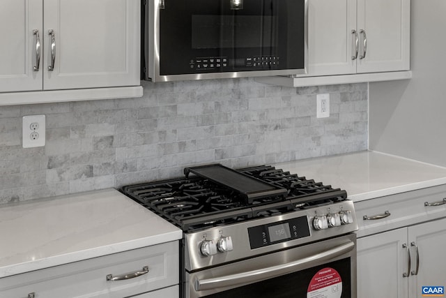 kitchen featuring white cabinets, light stone countertops, stainless steel appliances, and tasteful backsplash