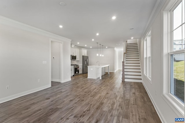 unfurnished living room featuring crown molding, sink, and dark hardwood / wood-style floors