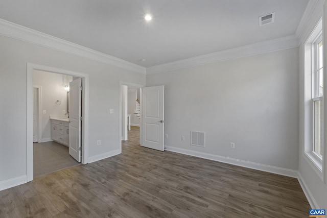 unfurnished bedroom featuring ensuite bath, crown molding, and dark hardwood / wood-style flooring