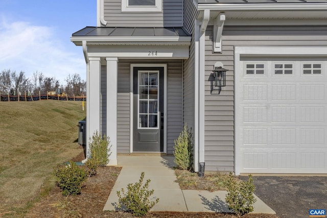 view of exterior entry featuring a lawn and a garage