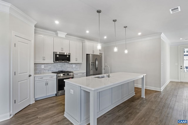 kitchen featuring sink, dark hardwood / wood-style floors, pendant lighting, a kitchen island with sink, and appliances with stainless steel finishes