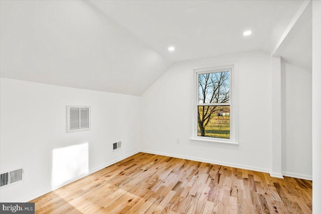 additional living space featuring light wood-type flooring and vaulted ceiling