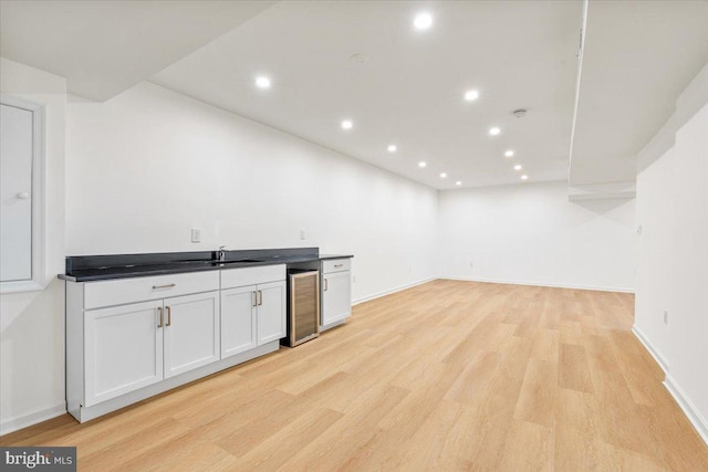 interior space with wine cooler, sink, white cabinets, and light hardwood / wood-style floors