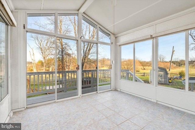 unfurnished sunroom featuring vaulted ceiling with beams and plenty of natural light