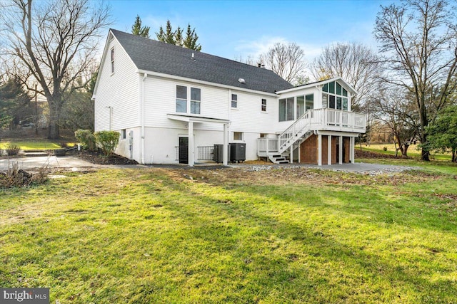 back of property featuring a sunroom, a lawn, central air condition unit, a wooden deck, and a garage