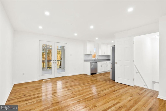 unfurnished living room featuring french doors, sink, and light hardwood / wood-style flooring