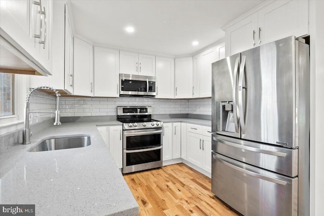 kitchen featuring white cabinetry, sink, light hardwood / wood-style floors, and appliances with stainless steel finishes