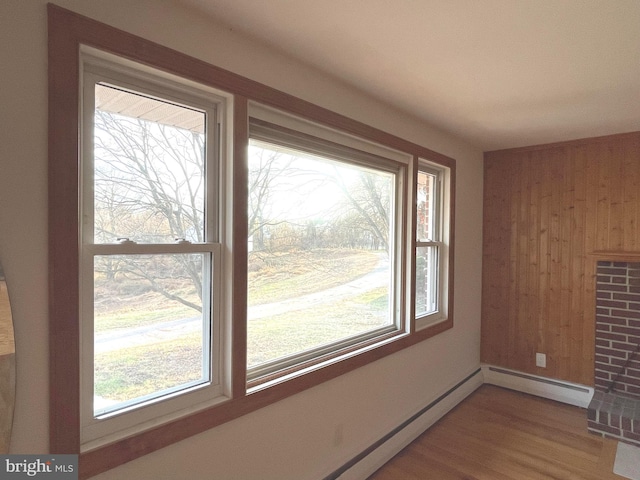 interior space featuring wood-type flooring, baseboard heating, and wood walls