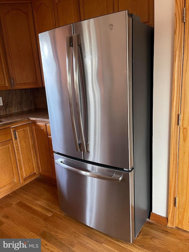 kitchen with decorative backsplash, stainless steel fridge, and light hardwood / wood-style floors