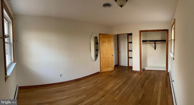 unfurnished bedroom featuring multiple windows, dark hardwood / wood-style floors, and baseboard heating