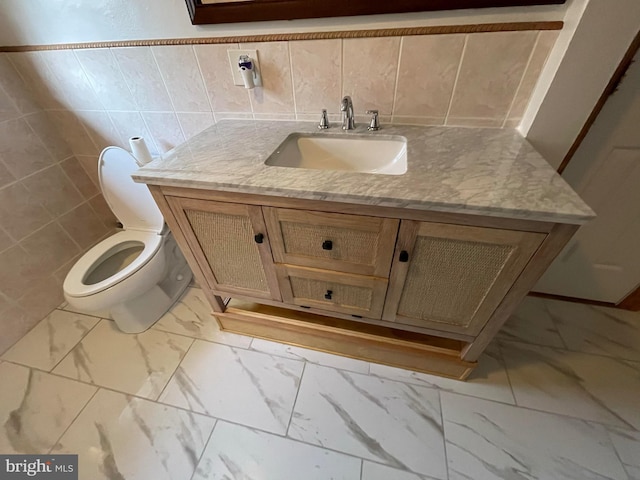 bathroom with vanity, toilet, and tile walls