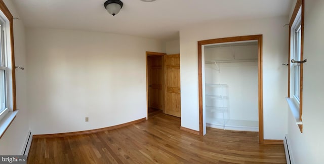 unfurnished bedroom featuring a baseboard radiator, light hardwood / wood-style flooring, and a closet