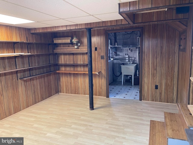 basement with wood walls and a drop ceiling