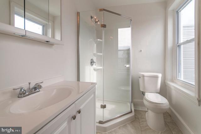 bathroom featuring tile patterned floors, vanity, toilet, and a shower with shower door