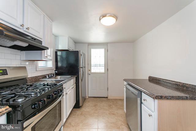 kitchen featuring white cabinets, sink, decorative backsplash, light tile patterned floors, and appliances with stainless steel finishes