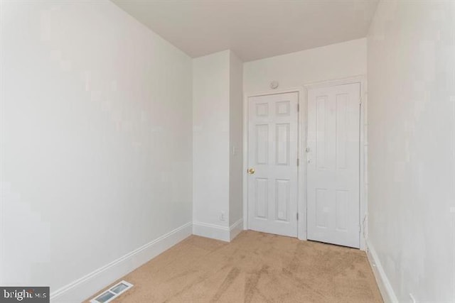 unfurnished bedroom with light colored carpet and a closet