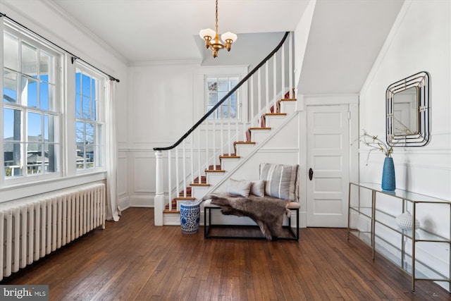 entrance foyer with crown molding, radiator heating unit, dark hardwood / wood-style floors, and an inviting chandelier