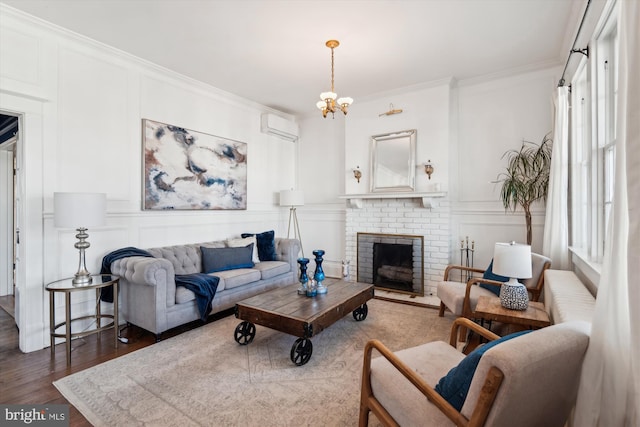 living room featuring a wall mounted air conditioner, a brick fireplace, crown molding, hardwood / wood-style floors, and a chandelier