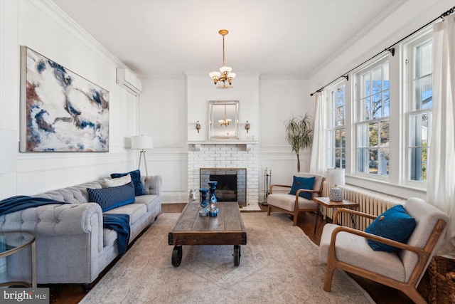 living room featuring a fireplace, a healthy amount of sunlight, a wall mounted air conditioner, and a notable chandelier