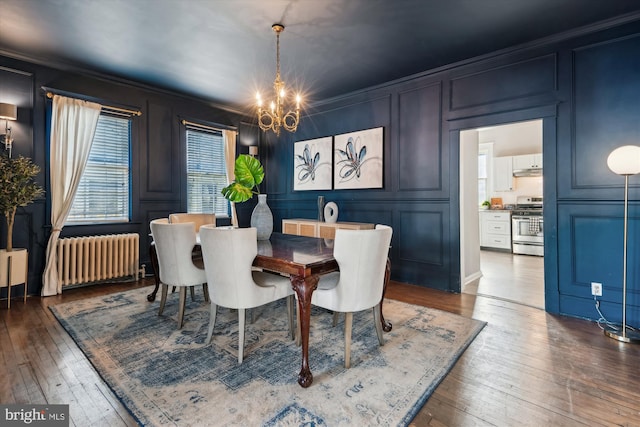 dining space featuring dark hardwood / wood-style flooring, radiator heating unit, ornamental molding, and a chandelier